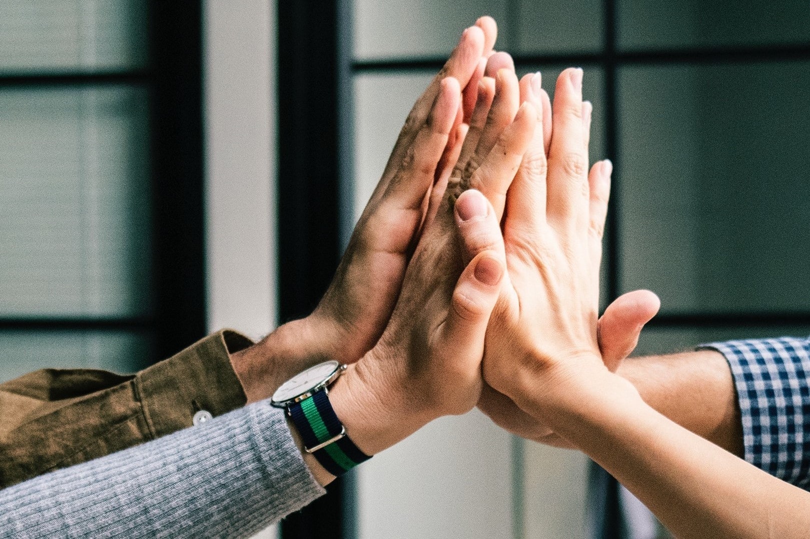 4 people high fiving (you can only see their hands and forearms)