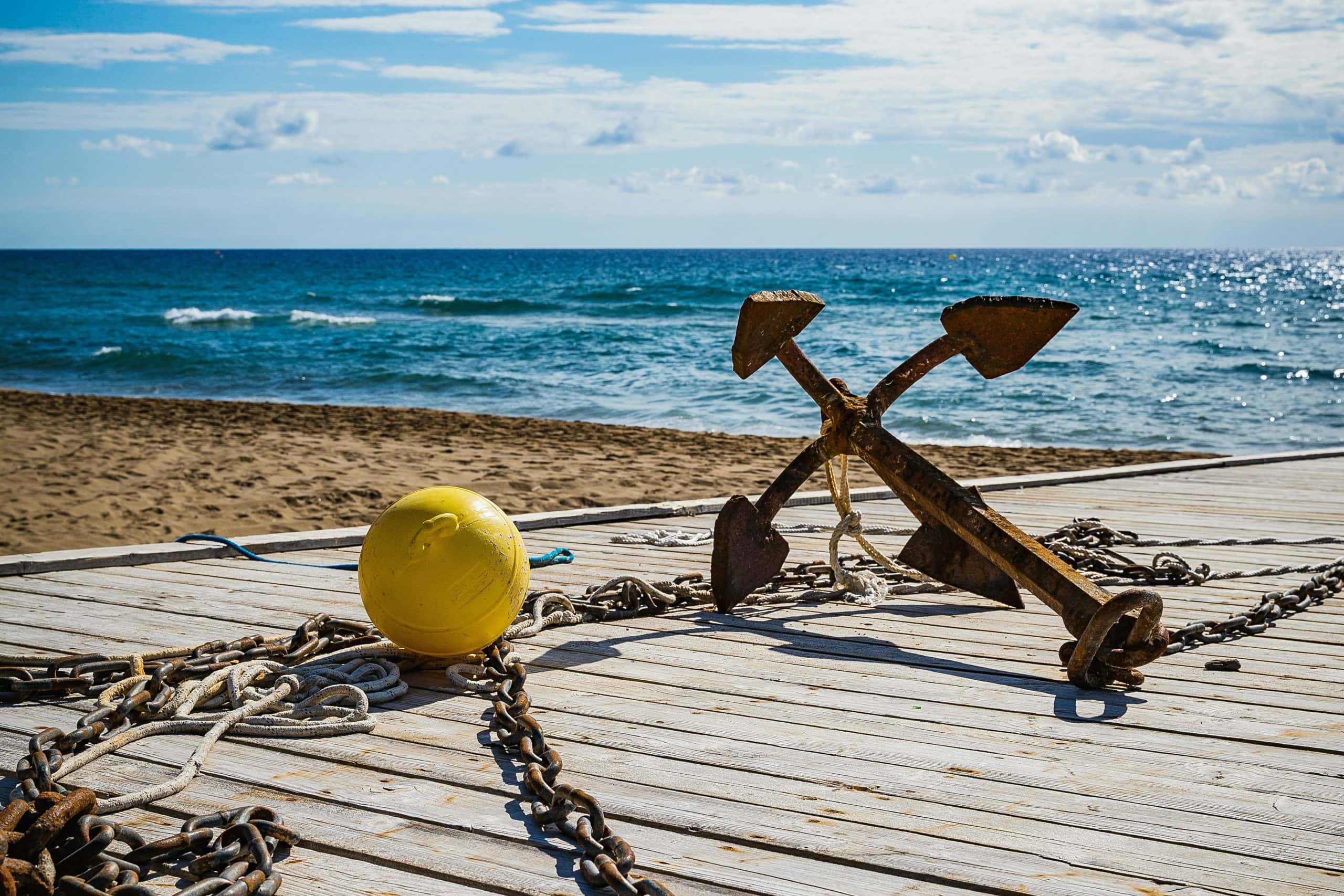 Real anchor and chains on a deck by the sea