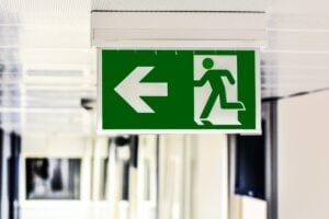 Green exit sign with a white arrow on a green background and a green man on a white background