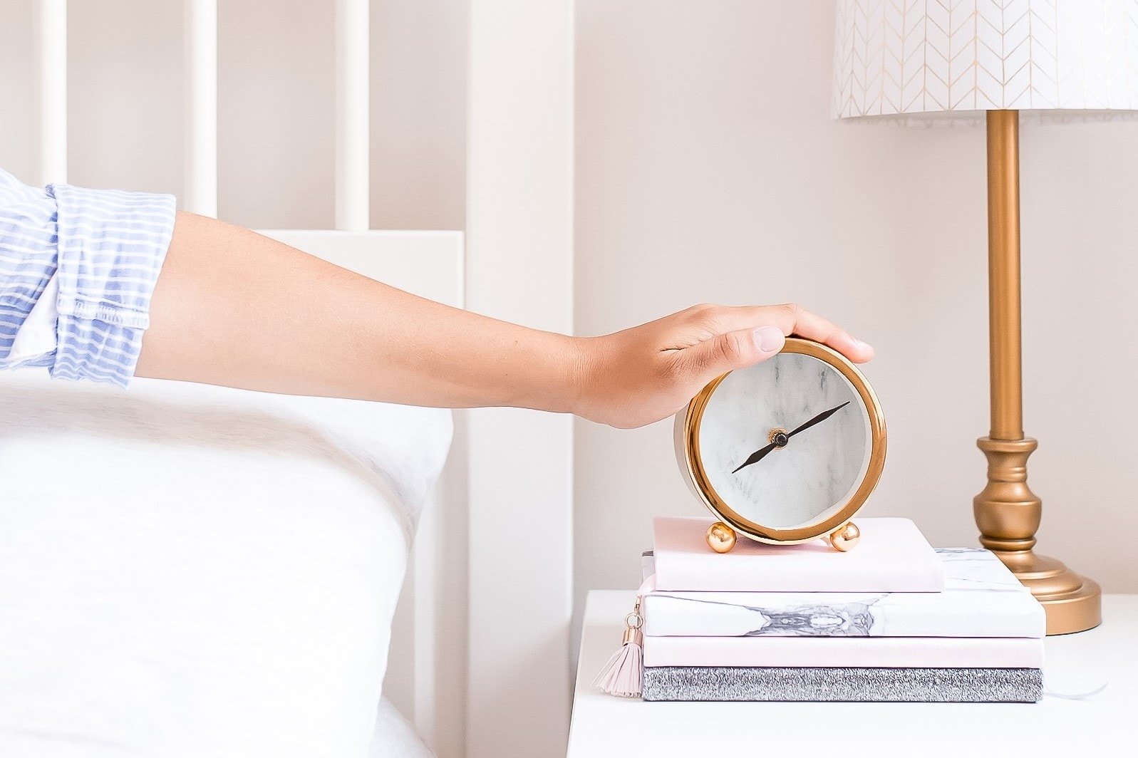 Woman reaching out of bed to turn off alarm clock