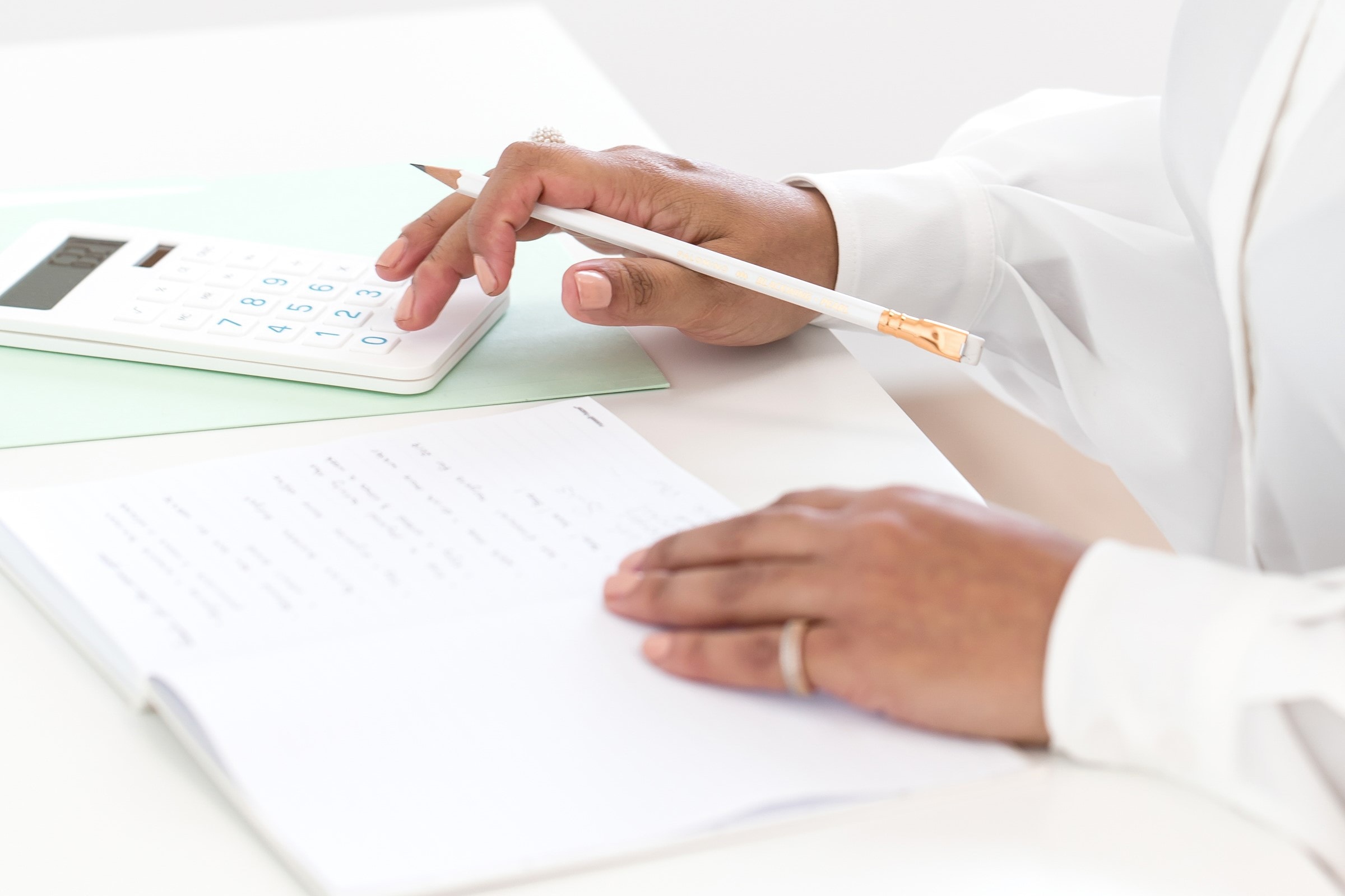 Woman writing on a notepad and tapping on a calculator