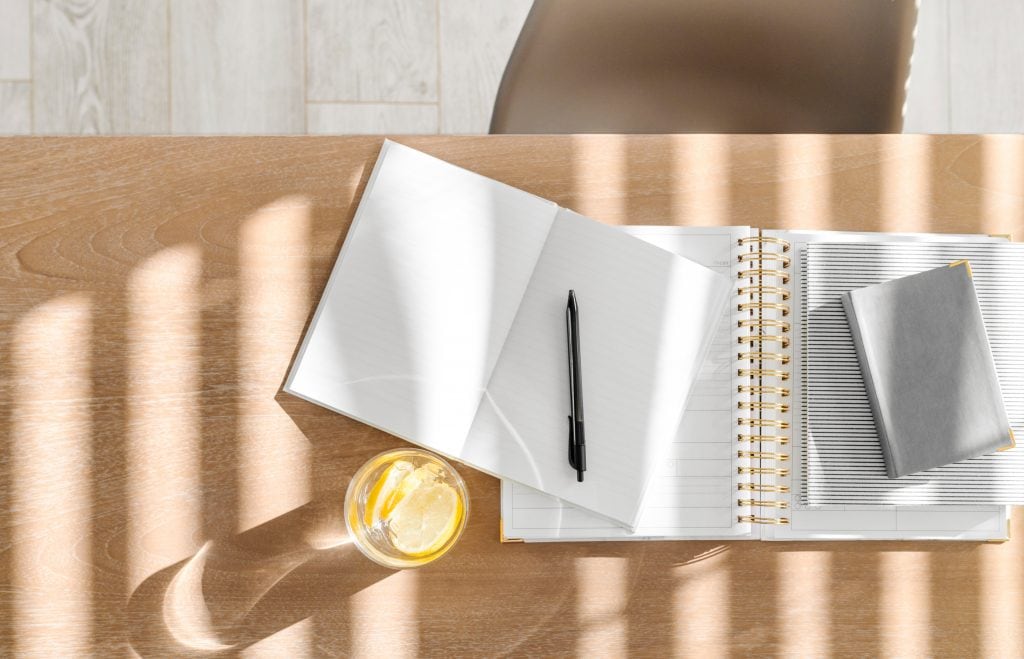 Notebooks, pen and glass of water on a desk