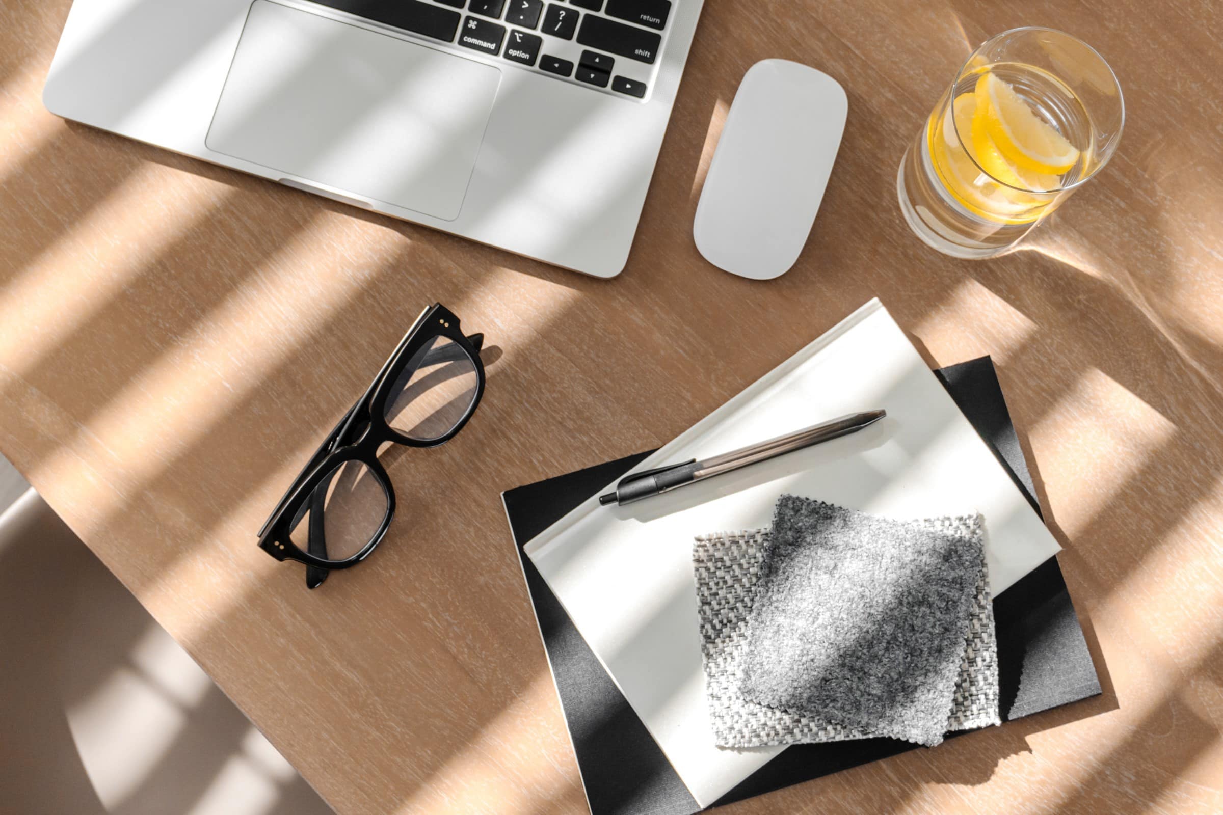 Notepads, laptop, mouse, glasses and glass of water on a desk