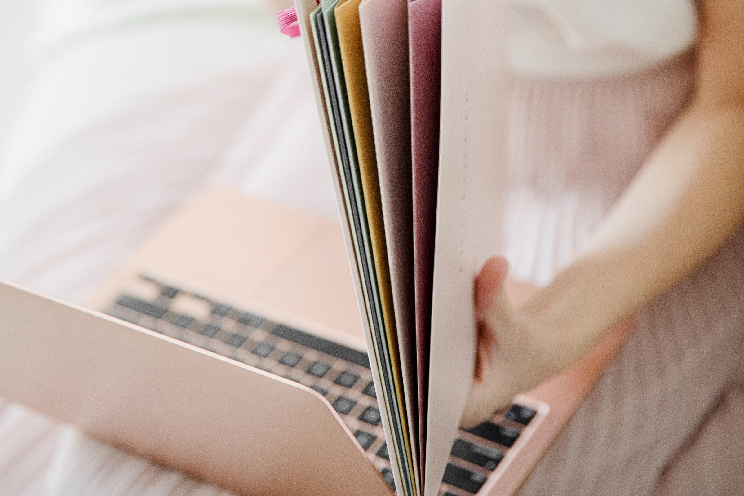 Woman holding folders. A rose gold laptop is on her lap.