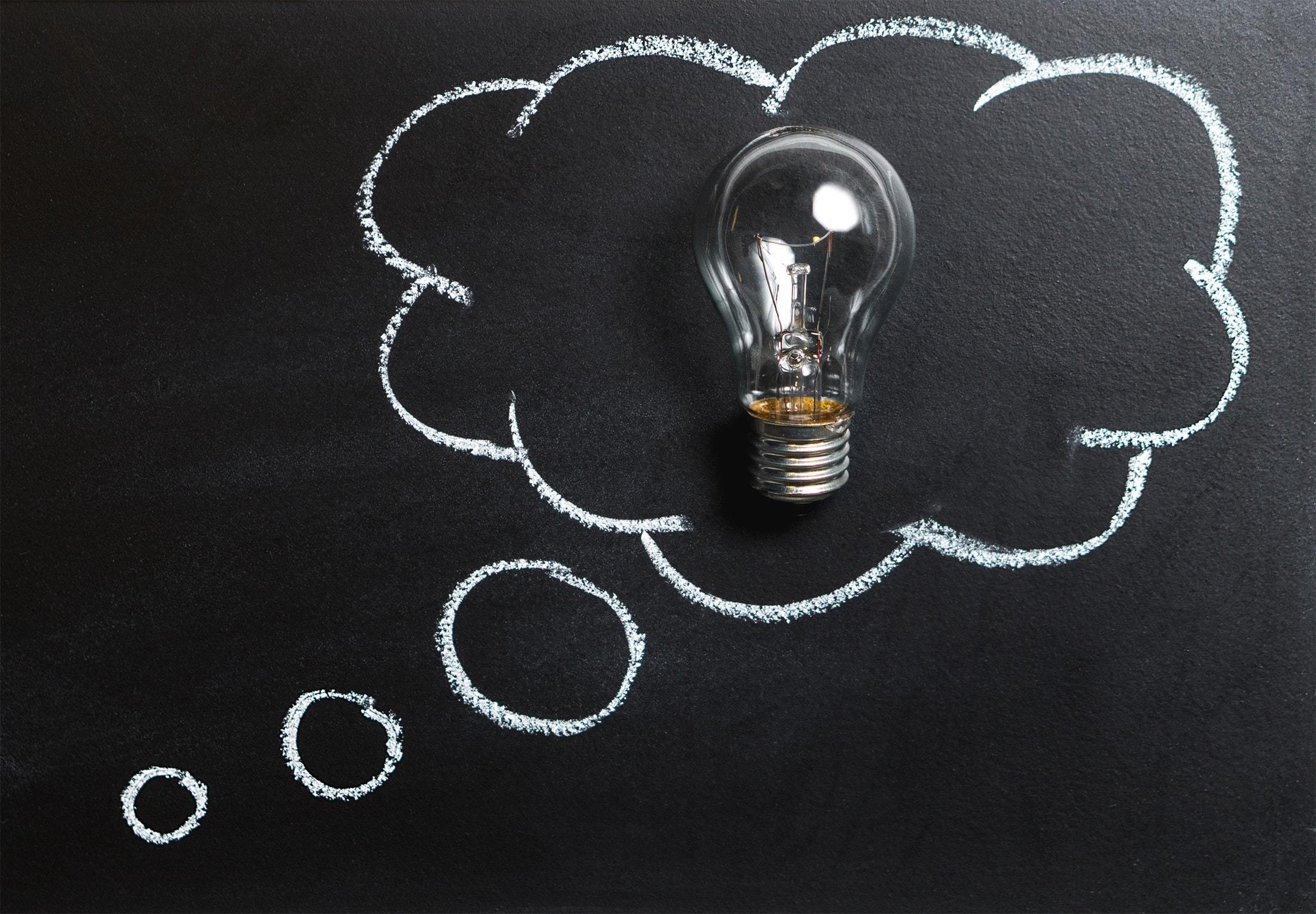 Lightbulb in a thought bubble/cloud drawn on a blackboard